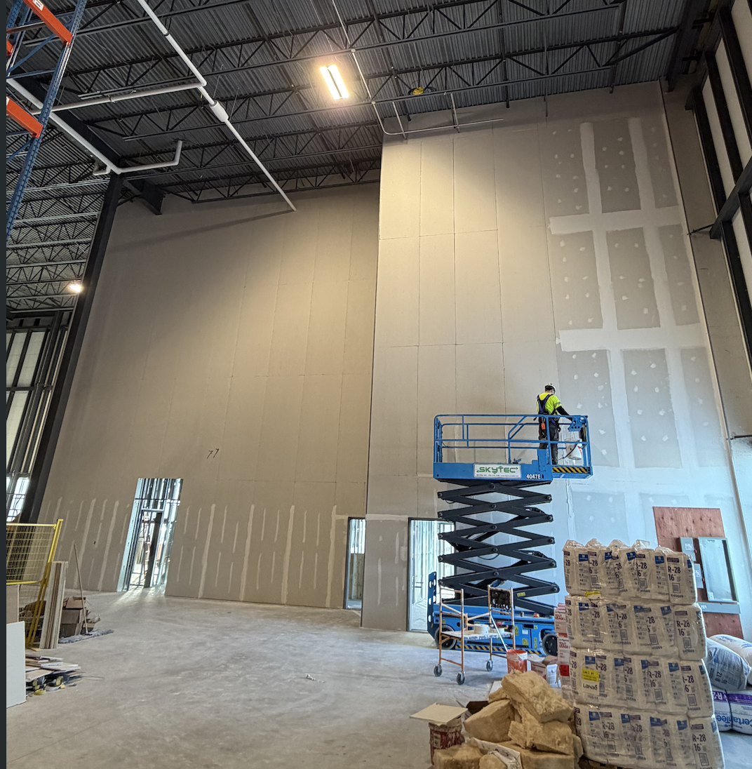 High-wall drywall taping from a scissor lift on a commercial project