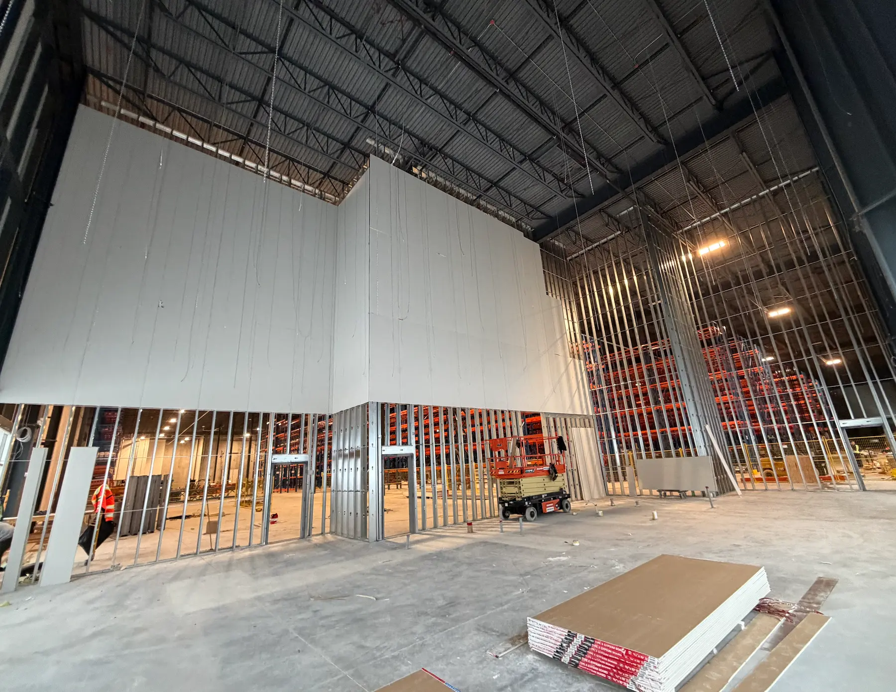 Steel framing and high-wall board installation in a distribution facility
