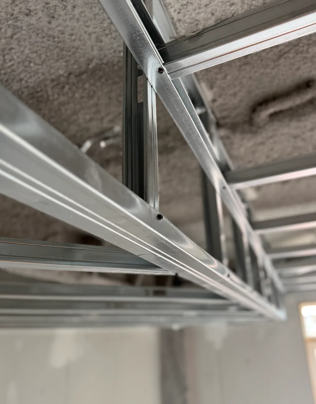 Suspended steel ceiling framing and bulkhead detail under a sprayed deck