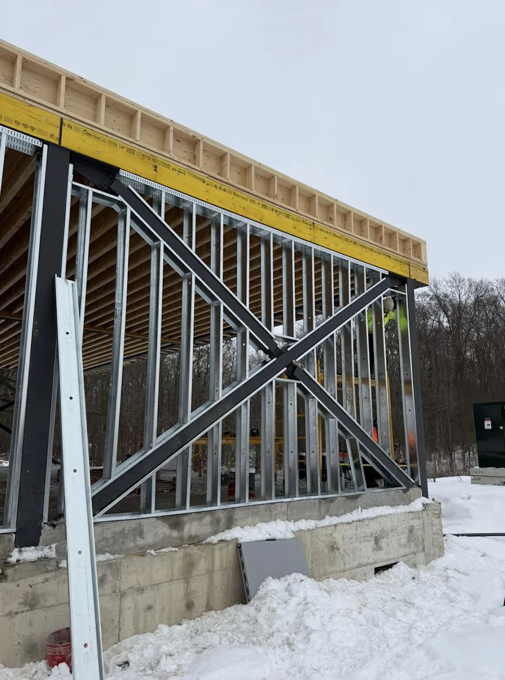Exterior load-bearing steel stud wall with cross bracing under a wood floor system